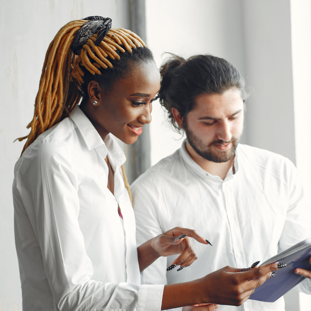 A young black women and white man reading a document together